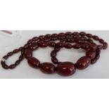 A faux cherry amber necklace, the oval graduated beads between approx 2.1 and 7.1cm, 63g, length