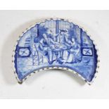 An 18th century Delft blue and white footed dish, of crescent form, decorated with figures within an