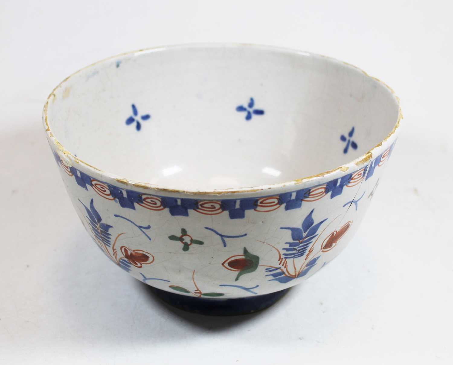 An 18th century English Delft bowl, decorated in shades of blue, brown and green, on circular foot