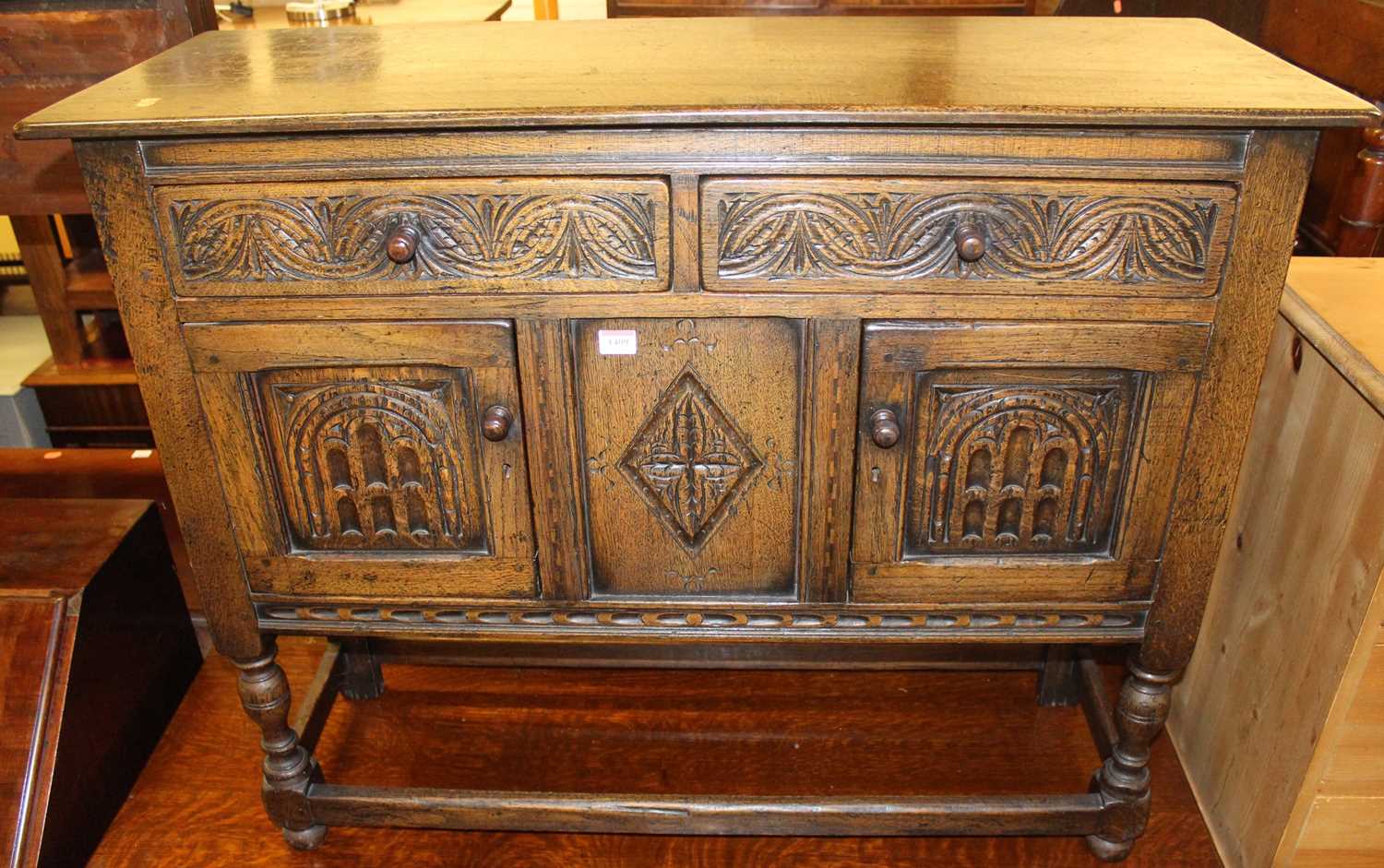 A small joined and relief carved oak dresser base having twin drawers and cupboard doors on turned