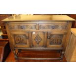 A small joined and relief carved oak dresser base having twin drawers and cupboard doors on turned