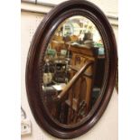 An early 20th century stained oval bevelled wall mirror, 94 x 69cm
