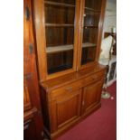 An Edwardian oak bookcase cupboard, with twin glazed upper doors, width 123cm