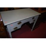 An Edwardian painted walnut? kneehole three-drawer dressing table, raised on ring turned supports,