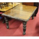 A circa 1900 carved oak extending dining table, having a wind-out action, single drop-in leaf, max