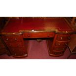 A Victorian mahogany inverted breakfront kneehole pedestal writing desk, having a gilt tooled red