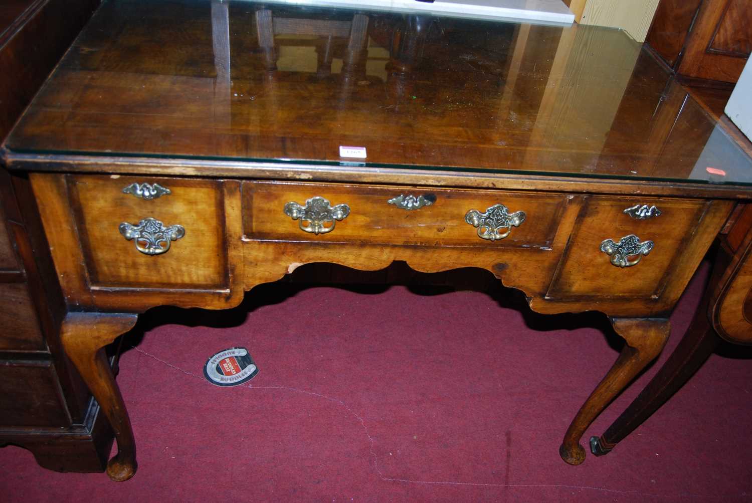 An early Georgian style figured walnut and feather banded three drawer kneehole lowboy, raised on