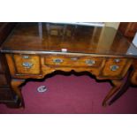 An early Georgian style figured walnut and feather banded three drawer kneehole lowboy, raised on