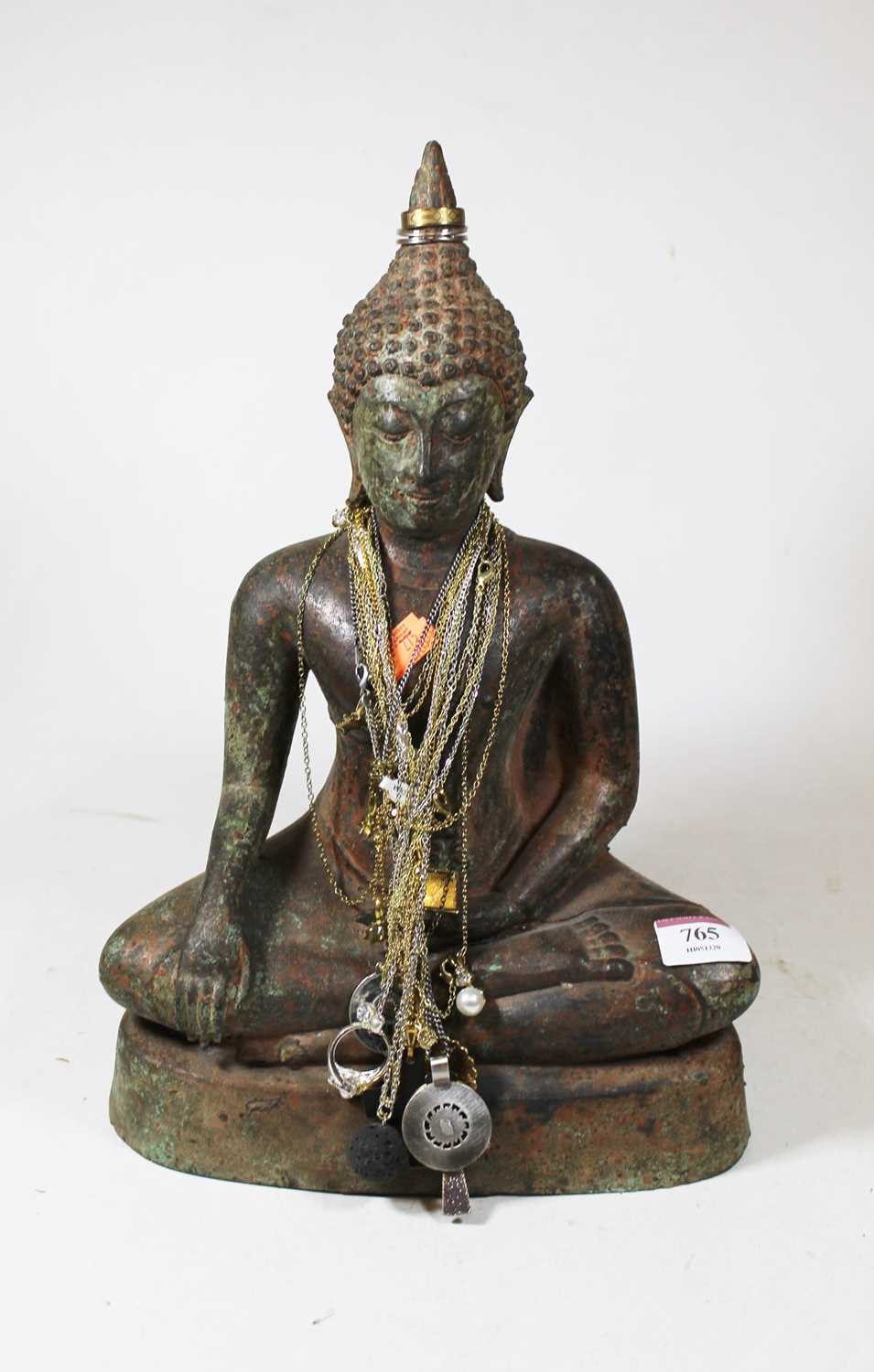 A cast metal model of a deity in typical seated lotus pose with various costume jewellery