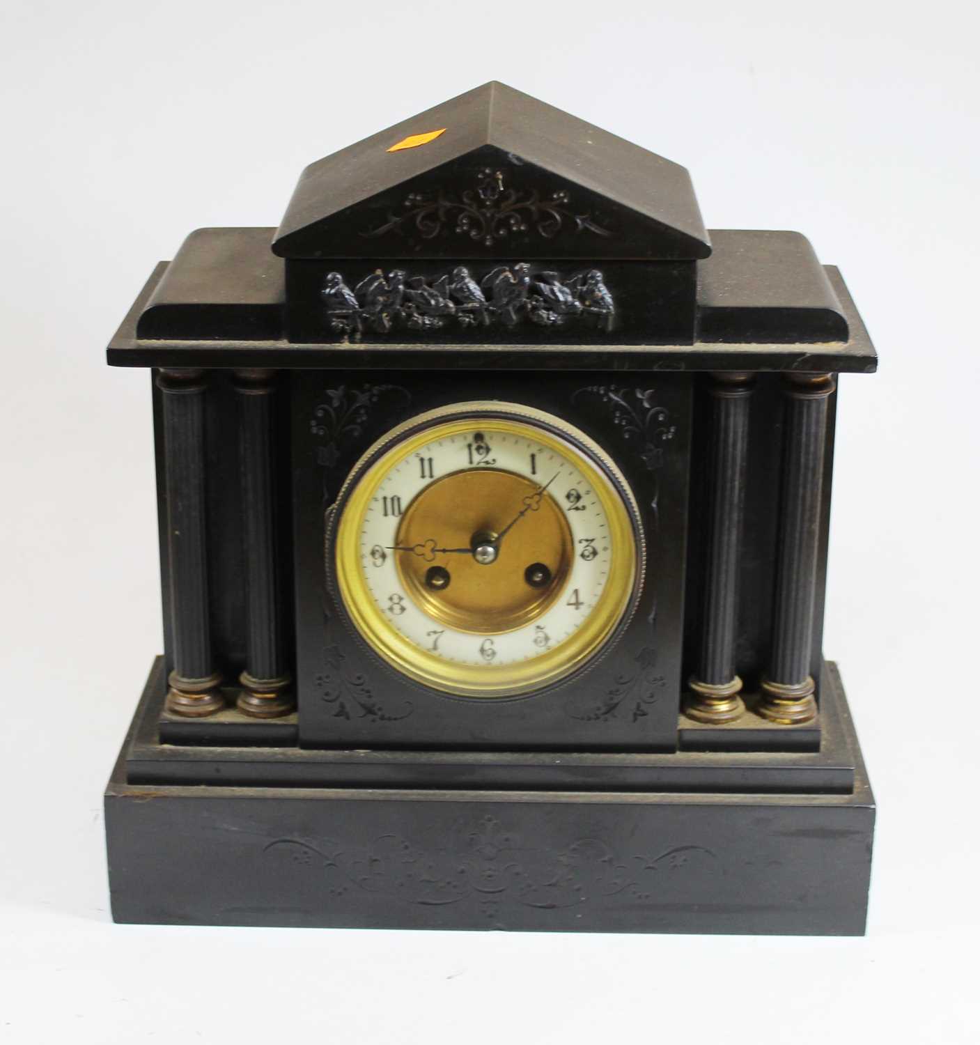 A Victorian black slate mantel clock of architectural form, relief decorated with birds, the dial