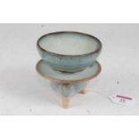 A Chinese stoneware flambe style stem cup of circular form mounted on similarly glazed tripod