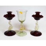 A pair of Venetian cranberry glass candlesticks, each with a stem in the form of a dolphin, together