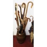 An early 20th century oak and brass bound umbrella stand, containing sundry walking sticks, shooting