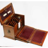 An early 20th century oak stationery box, the lid lifting to reveal a fitted interior, with burgundy
