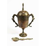 An eastern brass cup and cover, the finial above a repousse decorated body, flanked by twin handles,