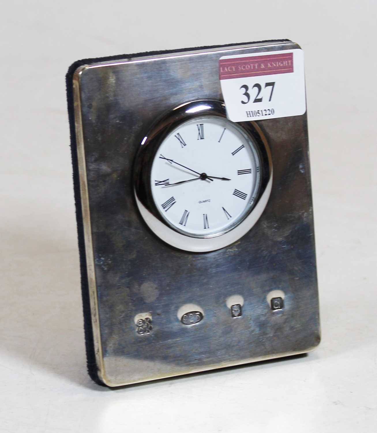 A modern silver clad easel mantel clock, having a circular dial with quartz movement, h.11cm