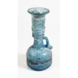 A Roman style blue glass bottle, the flared rim above a tubular neck, bulbous body and dimpled base,