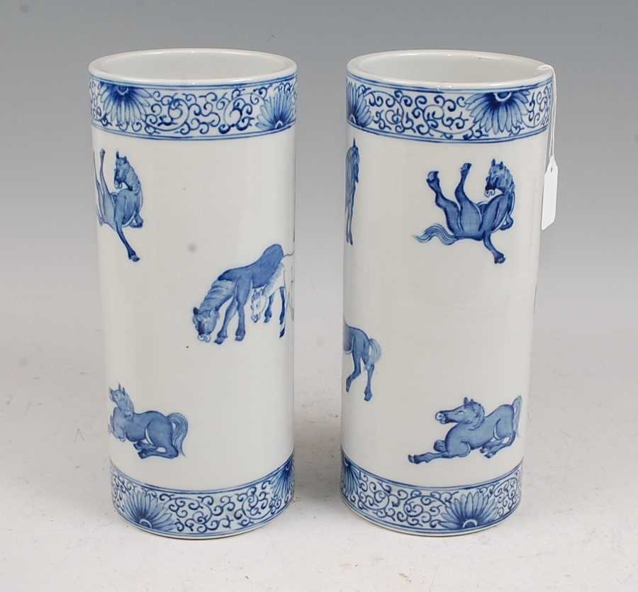 A pair of Chinese blue & white vases each of cylindrical form decorated with various horses within