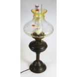 An early 20th century brass pedestal oil lamp, having yellow tinted glass shade, 56cm
