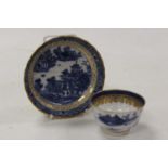 A 19th century tea bowl and saucer transfer printed in the Chinese style with figures and pagodas