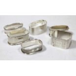 Six various English silver napkin rings, being either oval or rectangular, some with engine turned