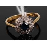 An 18ct gold, sapphire and diamond cluster ring, the four-claw set round cut sapphire in a