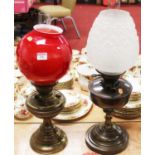 An early 20th century brass pedestal oil lamp, having red tinted opalescent glass shade; together
