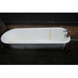 An early 20th century cast iron roll top bath with four removable feet