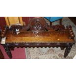 A late 19th century heavily carved oak ledgeback two seater hall bench, having raised and rolled
