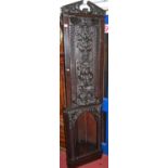 A stained and relief carved oak freestanding corner cupboard, of narrow form with single upper door