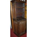 An antique ecclesiastical panelled oak credence shaped side cupboard having open upper shelving,