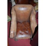 A pair of 1930s faded tan leather and studded club armchairs, raised on scroll square forelegs,