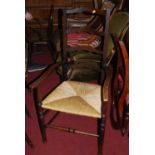 An early 20th century oak ladderback rush seat elbow chair, together with a matching single side