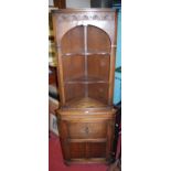 A contemporary moulded oak freestanding corner cupboard, having arched open upper section, height