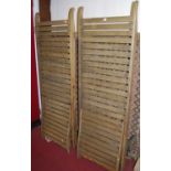 A pair of faded slatted teak sun loungers, each with ratchet adjustable backs