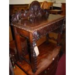 A late 19th century heavily carved oak ledgeback hall table, the mask and floral carved and