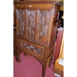 A good 19th century Gothic revival relief carved, joined and panelled oak cabinet on stand, with