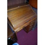 An early 20th century oak single pedestal kneehole roll top desk, having an arrangement of five