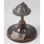 An early 20th century desk weight in the form of a lead Adrian pattern helmet, mounted on a column