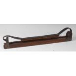 * An early 20th century oak and brass mounted game carrier, having an oak mounted leather strap