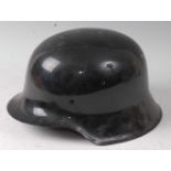 A German Model 1935 steel helmet, having later painted black exterior, lacking liner.Condition