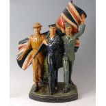 A WW II painted plaster figure group, depicting a soldier, sailor and airman beneath a Union flag,