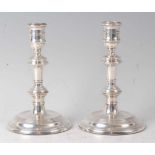 A pair of silver candlesticks, in the mid-18th century style, each having multi-knopped stems and on