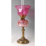 A Victorian lacquered brass and pink opaline glass pedestal oil lamp, having cranberry glass
