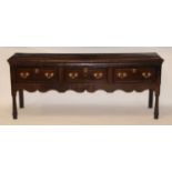 An 18th century oak dresser base, the two-plank top having a moulded edge over three frieze drawers,