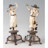 A pair of continental carved ivory table ornaments of standing female figures wearing bonnets,