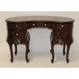A carved walnut kidney shaped kneehole writing desk, early 20th century, having a tooled leather