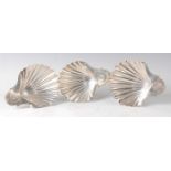 A set of three George III silver shell shaped butter dishes, each with bright cut engraving to the