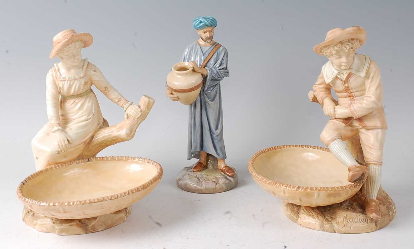 A pair of Royal Worcester figural comports by James Hadley, modelled as a boy and girl seated upon a