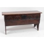 A circa 1700 joined oak two-plank coffer, the rectangular hinge top above a rosette carved frieze,